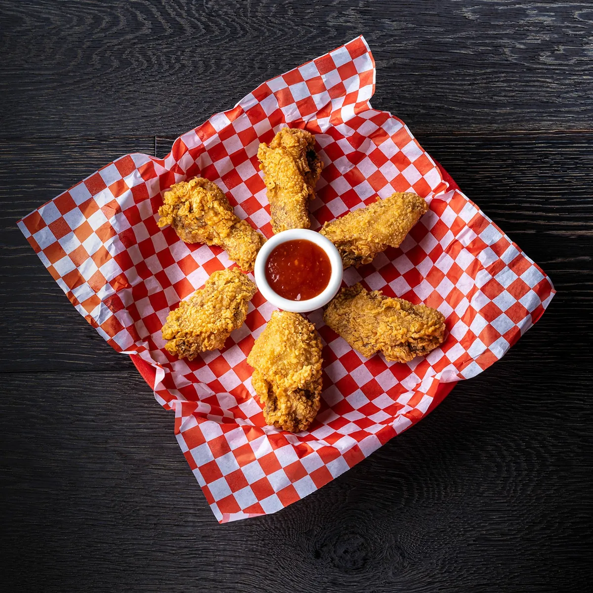 Wing dings arranged around a cup of cocktail sauce